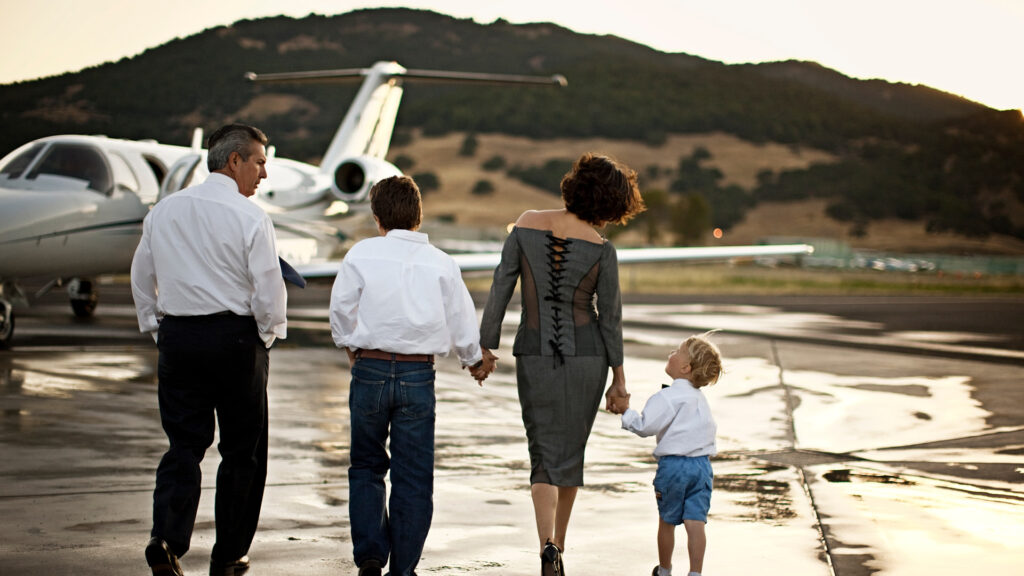 Family of four boarding Avianese private jet while pilot waits to greet them inside